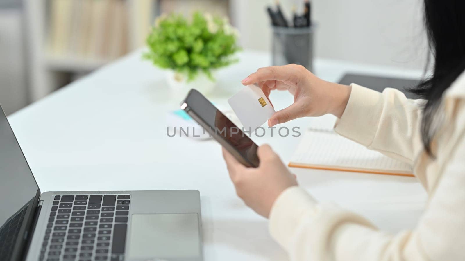 Cropped shot of woman hand holding credit card and smartphone, paying online, entering information, shopping online.