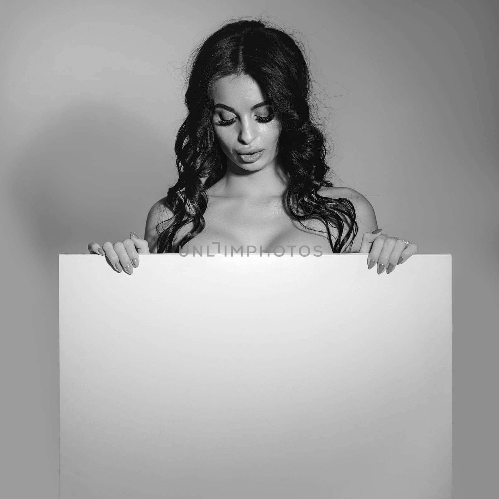 Sexy naked brunette woman holding empty board. attractive girl with blank board with copy space. black and white