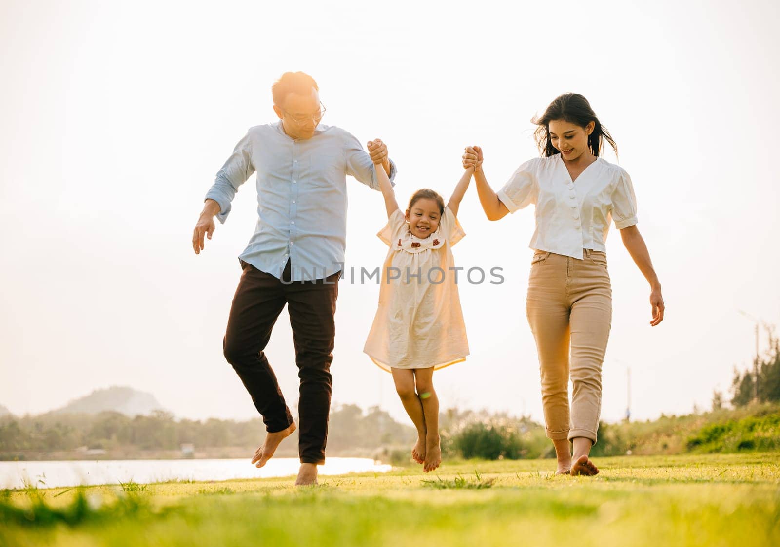 Asian family walking and holding hands in a beautiful springtime park, enjoying the nature and the togetherness, feeling happy and cheerful, Happy family day