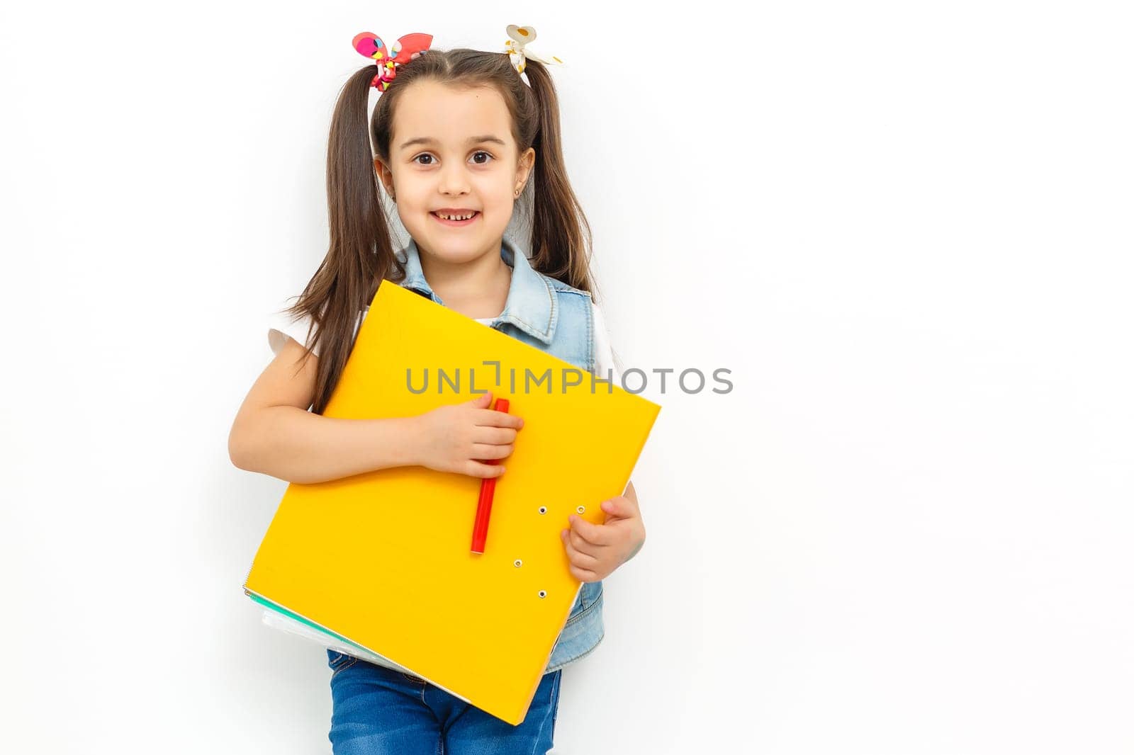 happy sweet little school girl carrying schoolbag backpack and books smiling in education and back to school concept isolated on white background