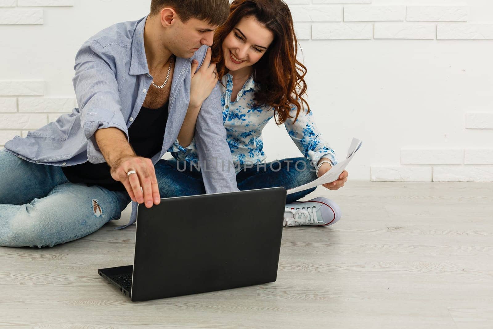 Portrait of happy young couple using laptop on gray background.