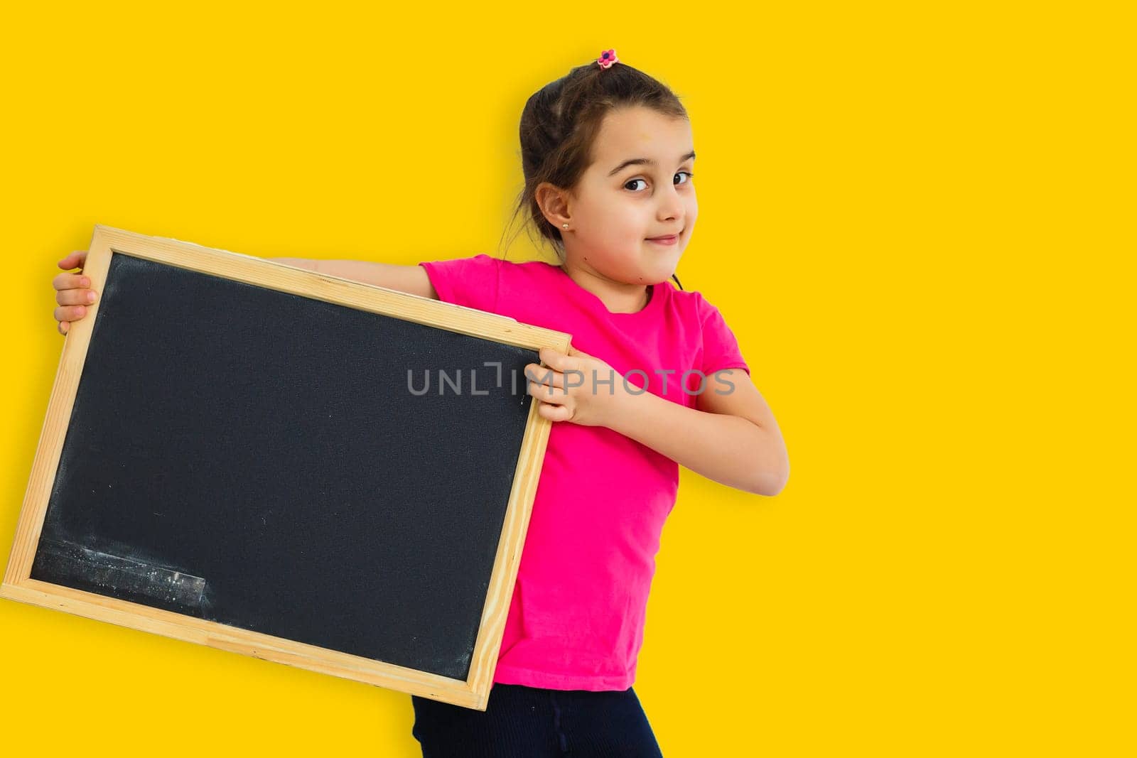 Little asian girl holding black board on yellow background by Andelov13
