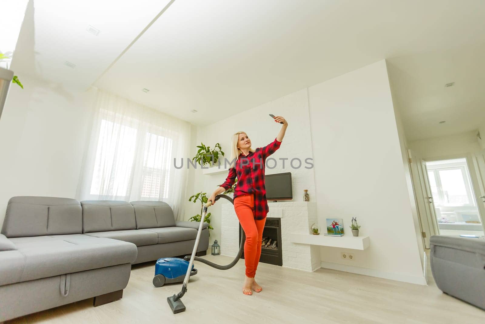 Young woman using vacuum cleaner at home by Andelov13