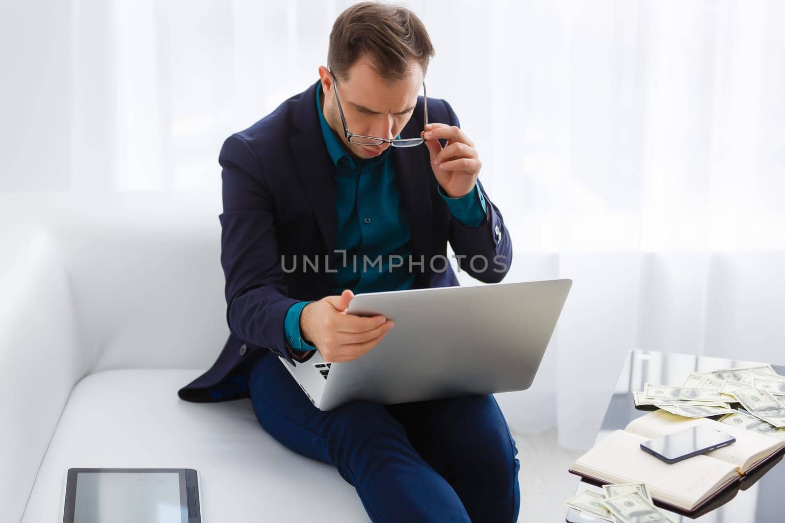 Doubtful young man looking up while working on laptop at home
