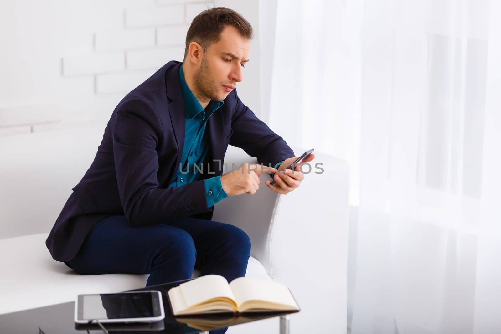 young businessman on a white sofa on white background by Andelov13