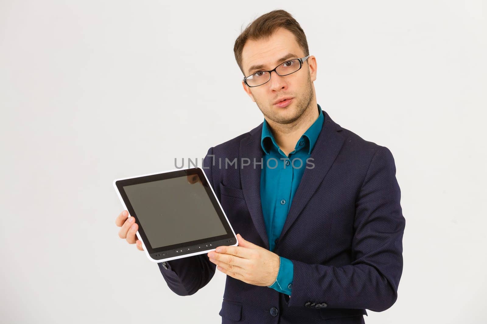 Portrait of a serious businessman holding tablet computer and looking at camera isolated on a white background. by Andelov13