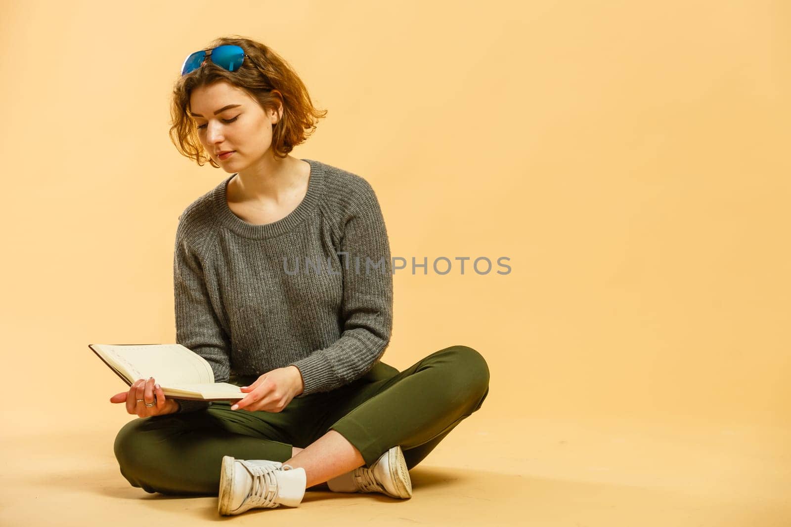 Smiling young brunette business woman in white shirt glasses isolated on yellow background. Achievement career wealth business concept. Mock up copy space. Writing notes in notebook, looking aside