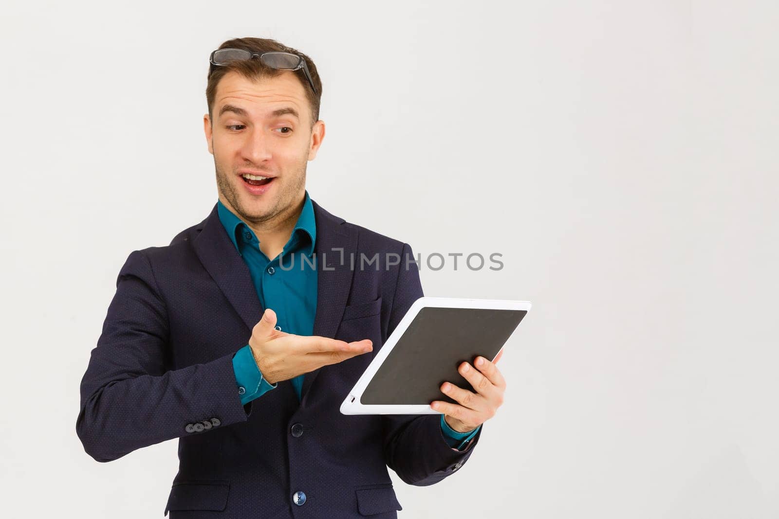Using modern technologies. Handsome young man in shirt looking at his digital tablet and smiling while standing against background