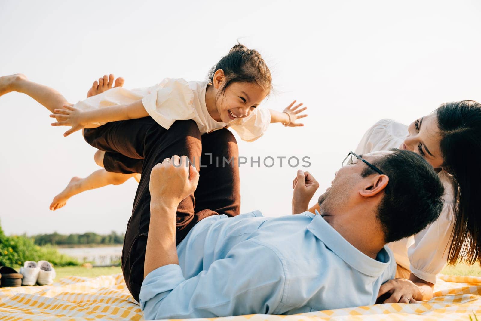 Happy family father holding small kid daughter on straight legs with mother by Sorapop