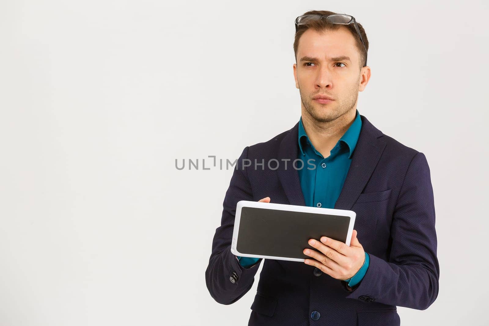 Using modern technologies. Handsome young man in shirt looking at his digital tablet and smiling while standing against background
