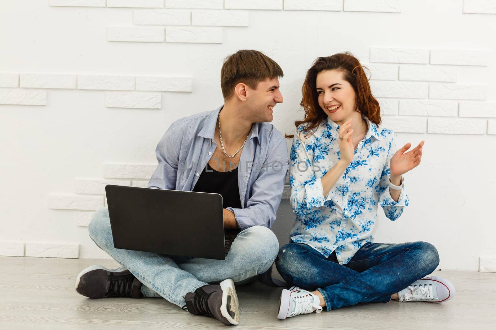 Portrait of happy young couple using laptop on gray background.