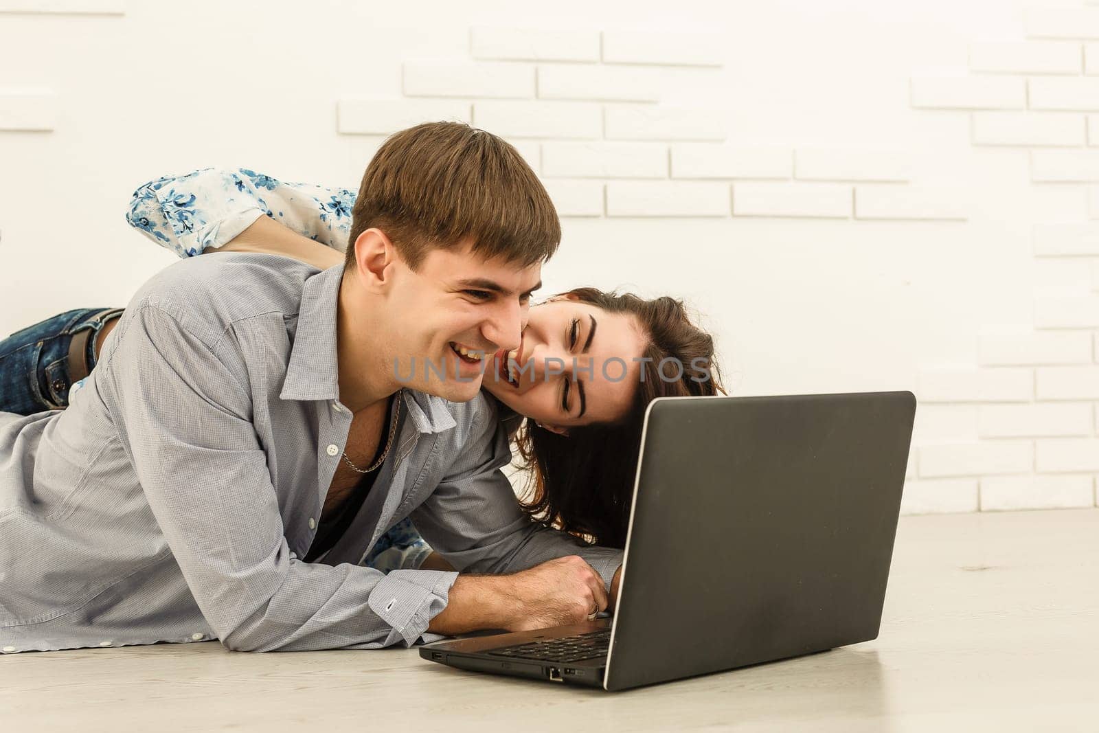 Portrait of happy young couple using laptop on gray background.