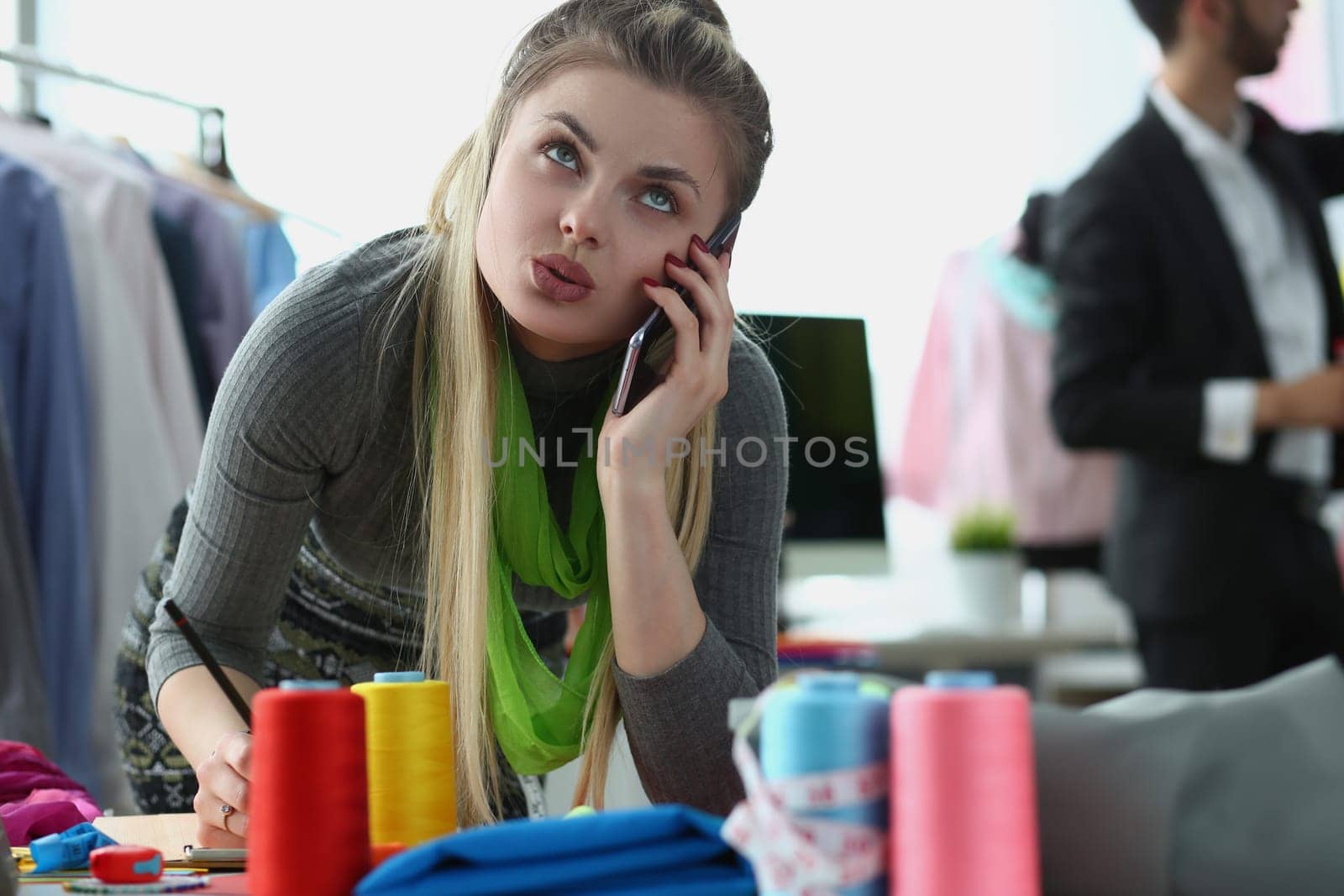 Creative designer manager stylist offers tailoring design option over phone. Seamstress woman talking to client on smartphone