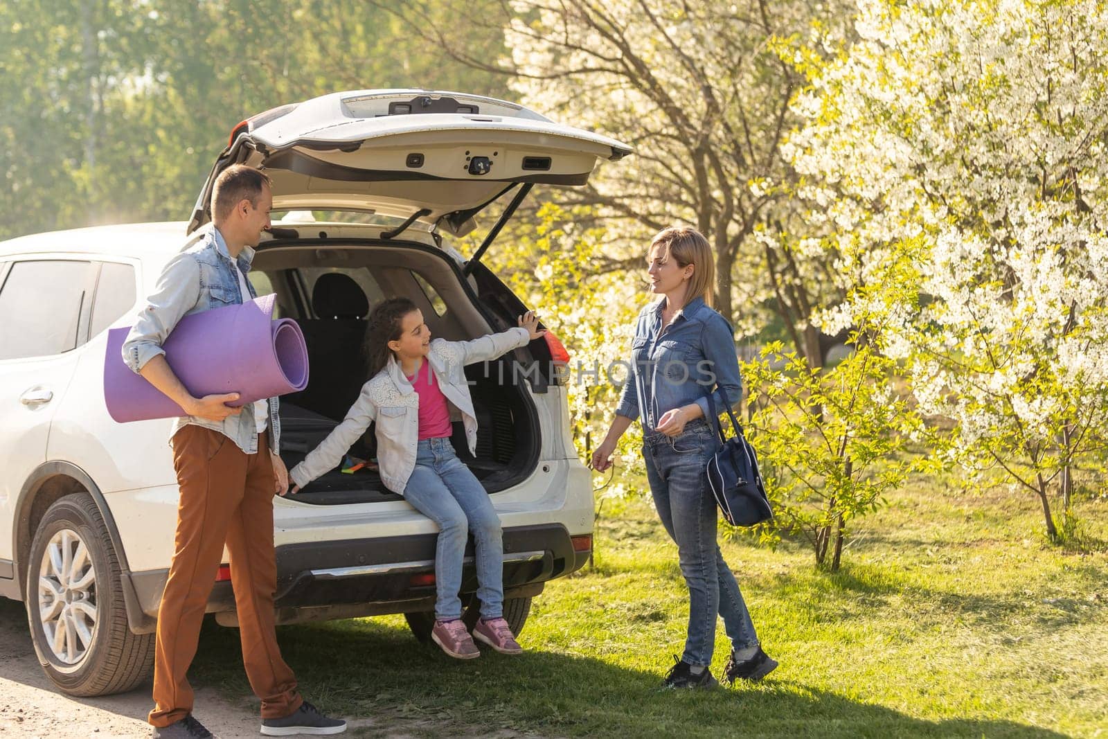 Family with kids sitting in car trunk.