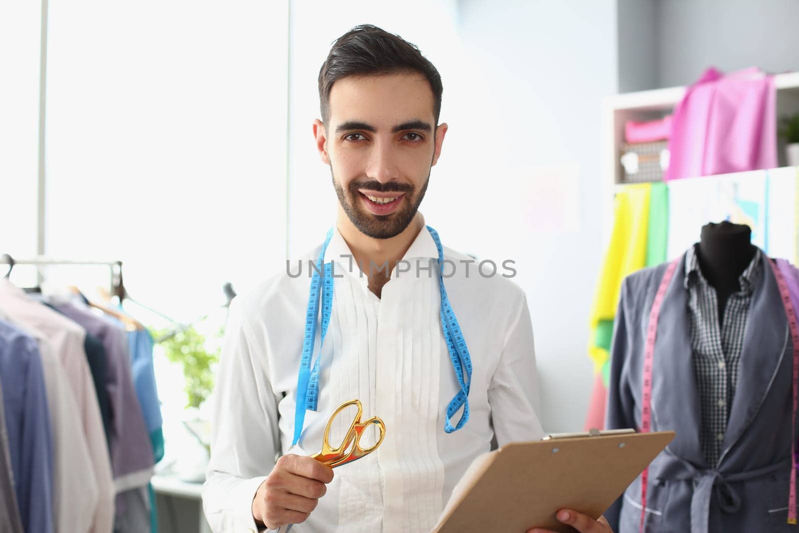 Portrait of male fashion designer stylist in atelier. Sewing fashionable modern clothes in creative workshop