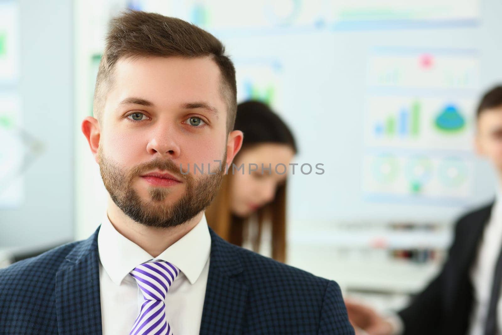 Portrait of serious businessman in background business partners colleagues by kuprevich