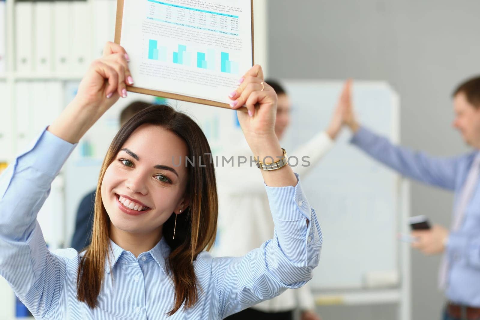 Portrait of smiling beautiful businesswoman holding clipboard with financial charts in background successful team. Successful business deal and partnership