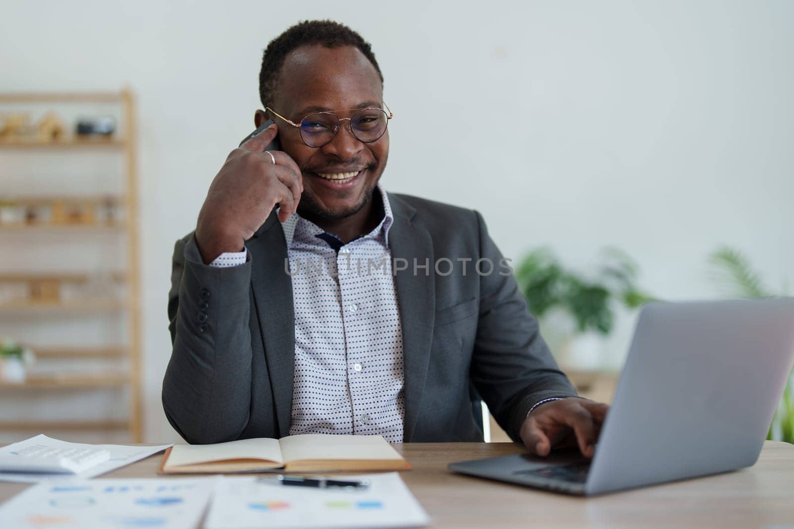 middle aged man American African using smart phone mobile and laptop computer with planning working on financial document, tax, exchange, accounting and Financial advisor.