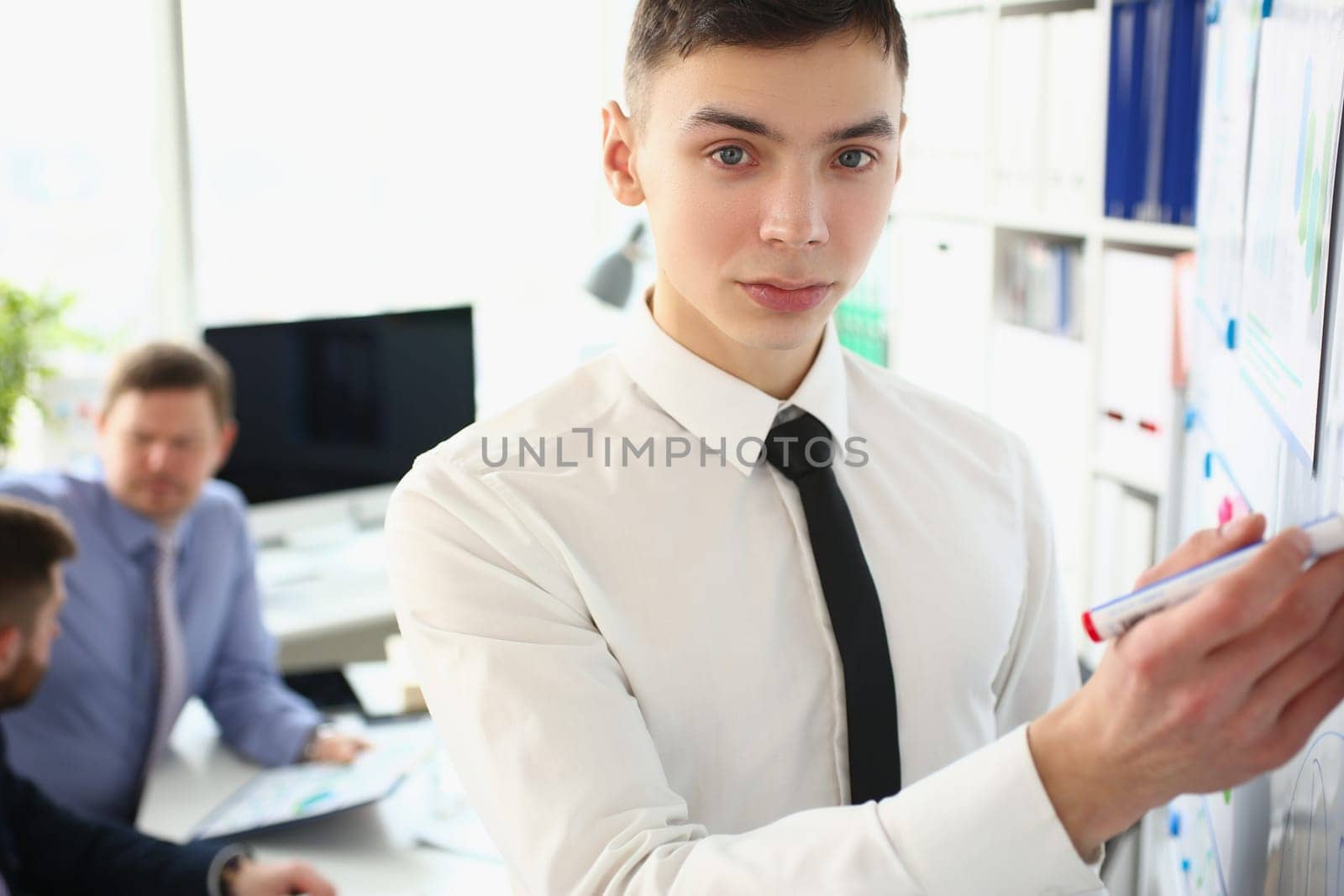 Portrait of man stands with marker near educational white board and holds business lecture. Mentor coach at conference concept