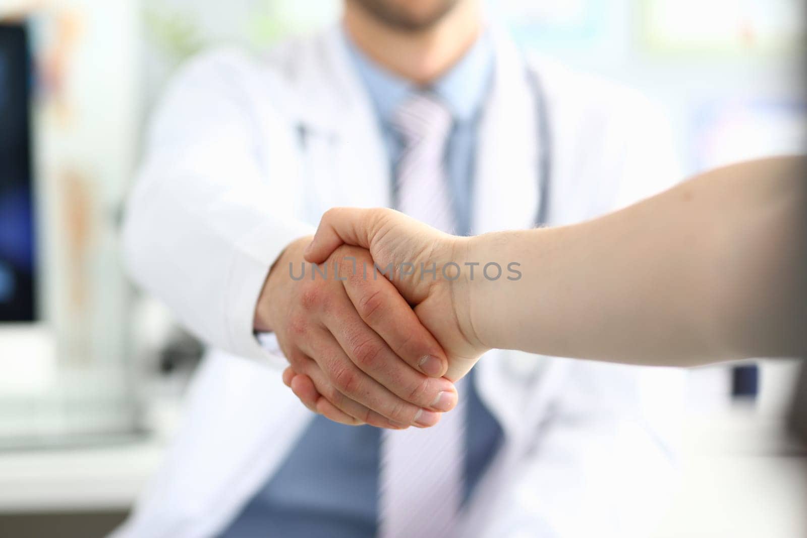 Doctor shaking hands with patient in clinic and thanking handshake for excellent treatment. Trust partnership and health insurance concept