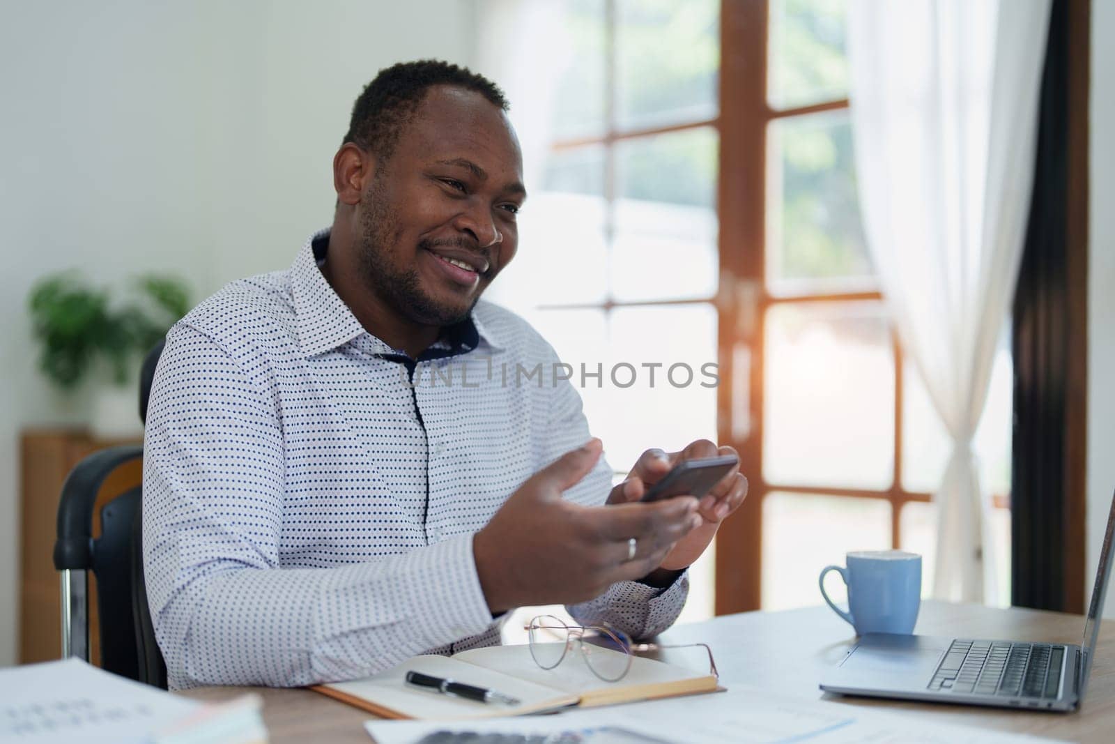 middle aged man American African using smart phone mobile and laptop computer with planning working on financial document, tax, exchange, accounting and Financial advisor.