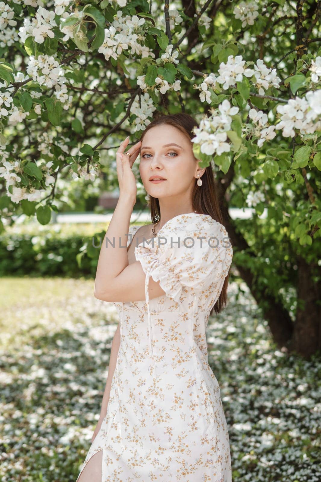 An attractive long-haired woman walks in the spring in the park of blooming apple trees. by Annu1tochka