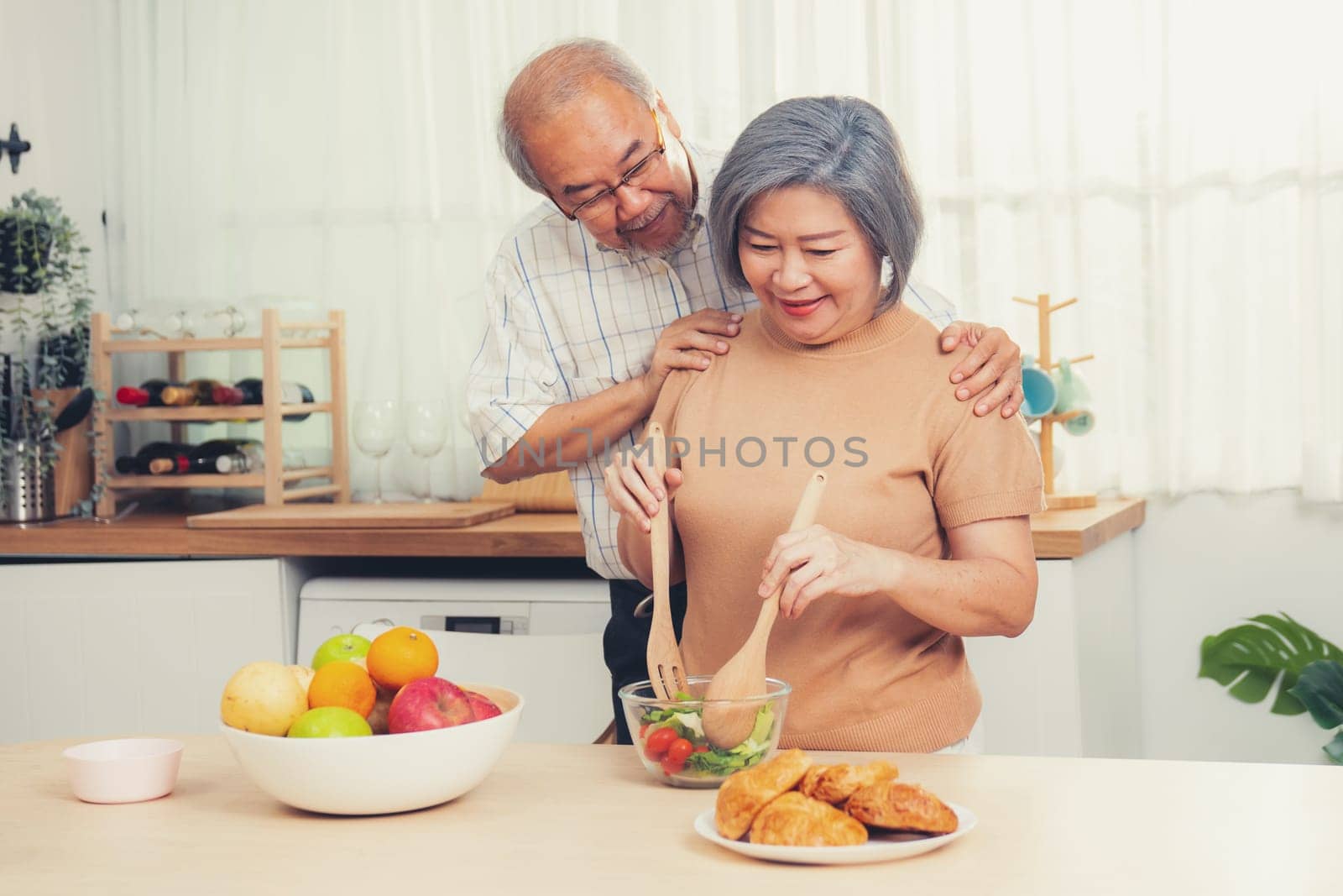 Contented senior couples who are happy to cook together with bread veggies and fruit in their kitchen.