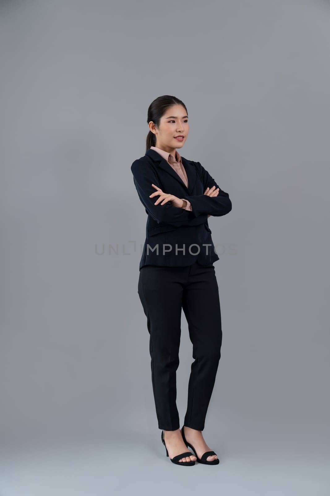 Confident young businesswoman stands on isolated background. Enthusiastic by biancoblue