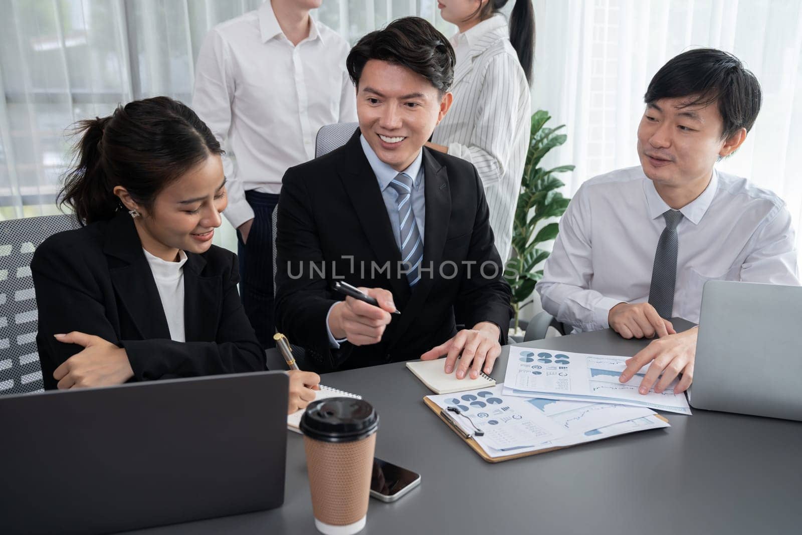 Harmony in office concept as business people analyzing dashboard paper together in workplace. Young colleagues give ideas at manager desk for discussion or strategy planning about project.