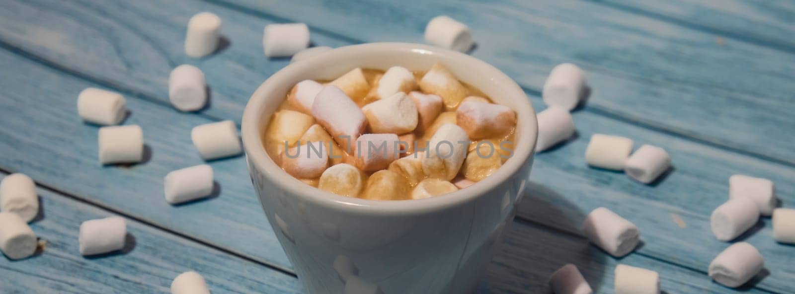 Banner Close up of Cup hot chocolate marshmallows cacao. Cozy Coffee with marshmallows on wooden blue background. Copy space for text. Wallpaper design. Sweet unhealthy food