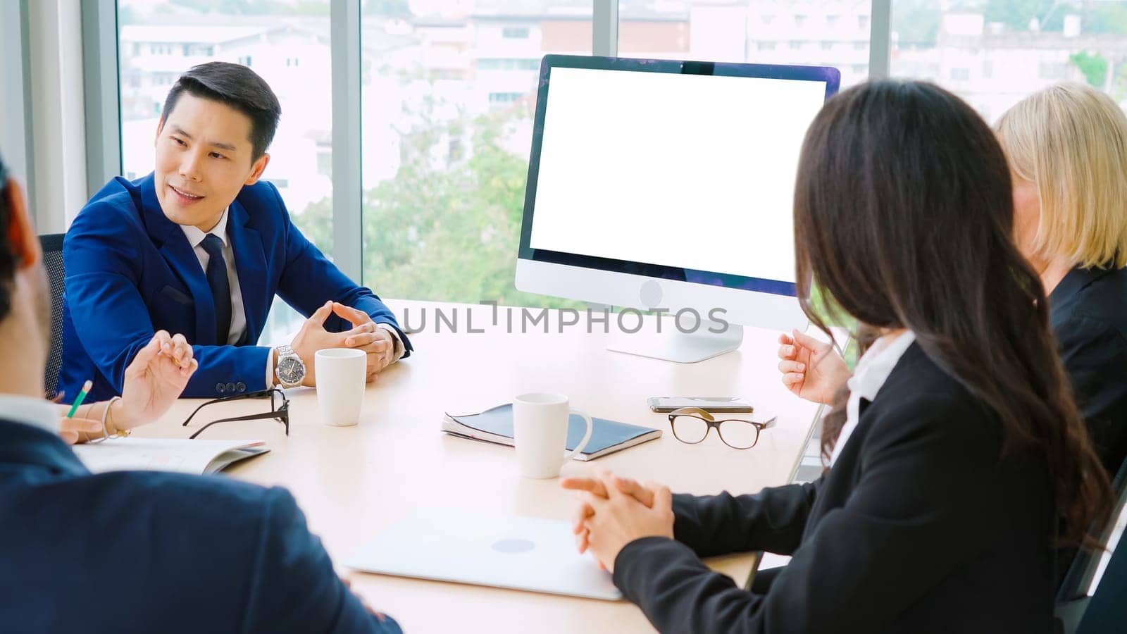 Business people in the conference room with green screen chroma key TV or computer on the office table. Diverse group of businessman and businesswoman in meeting on video conference call .