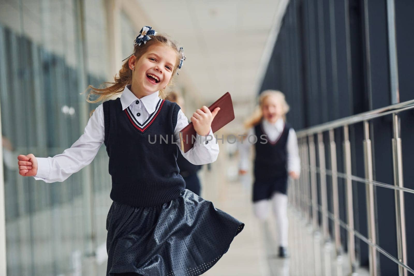 Active school kids in uniform running together in corridor. Conception of education by Standret