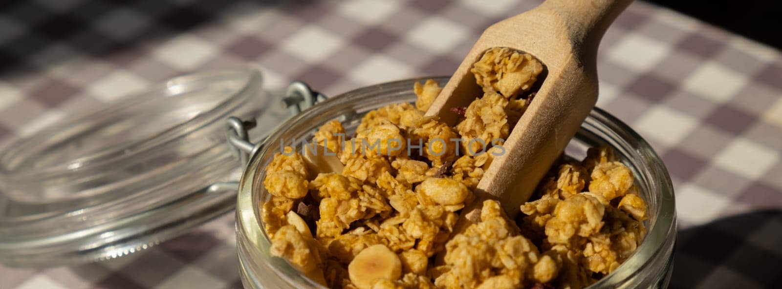 Homemade granola with nuts and seeds in eco glass jar. Healthy snack on breakfast. Granola, homemade muesli from oatmeal, raisins, honey, cranberry, flax, almond, macadamia, cashew, freshly baked