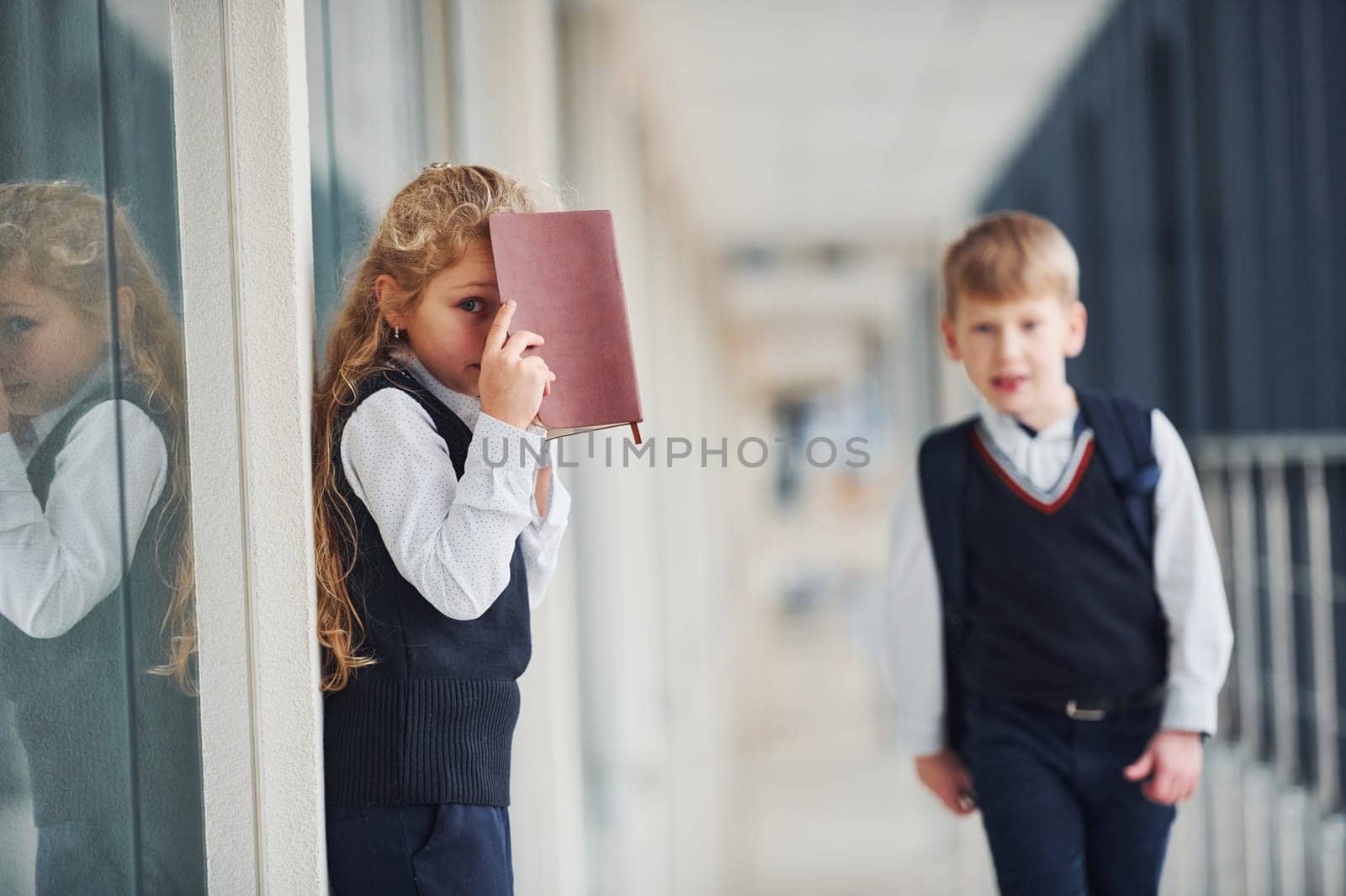 School kids in uniform with books together in corridor. Conception of education.