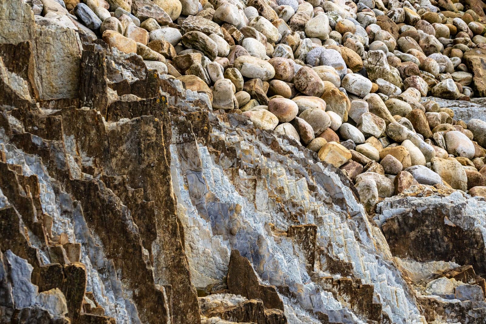 Pebbles and boulders on the seashore. Rocky ocean shore