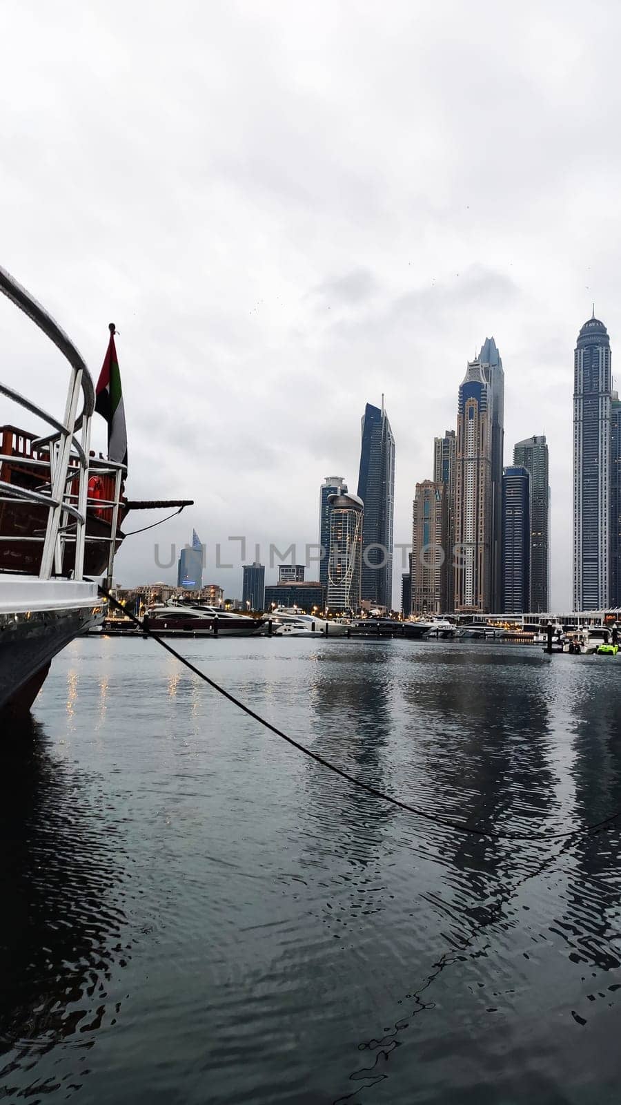 Yachts and boats in Dubai Marina, United Arab Emirates. Vertical photo, view of skyscrapers near the pier