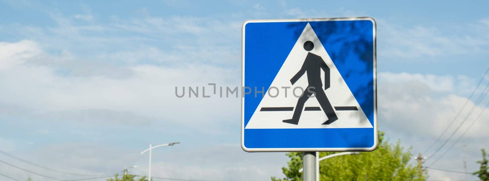 Vertical signage of crosswalk over cloudy sky, road sign pedestrian crossing. Attention road sign. Outdoors