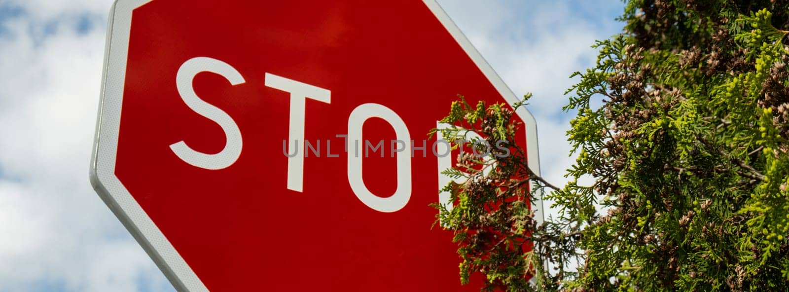 Red stop sign on metal pole on street. Road attention sign on cloudy background. Outdoors