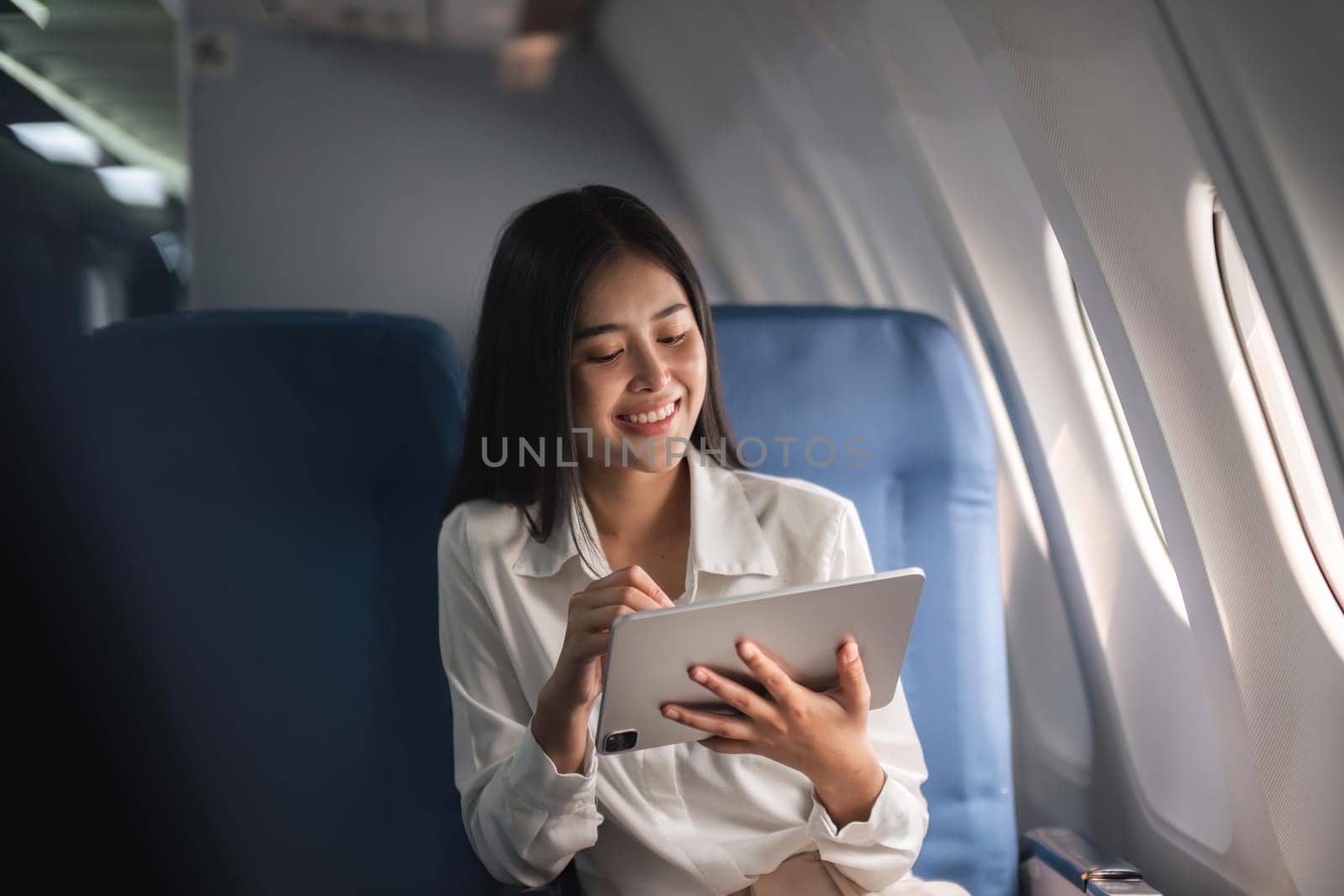 Beautiful asian travel woman watching movie on digital tablet in airplane.