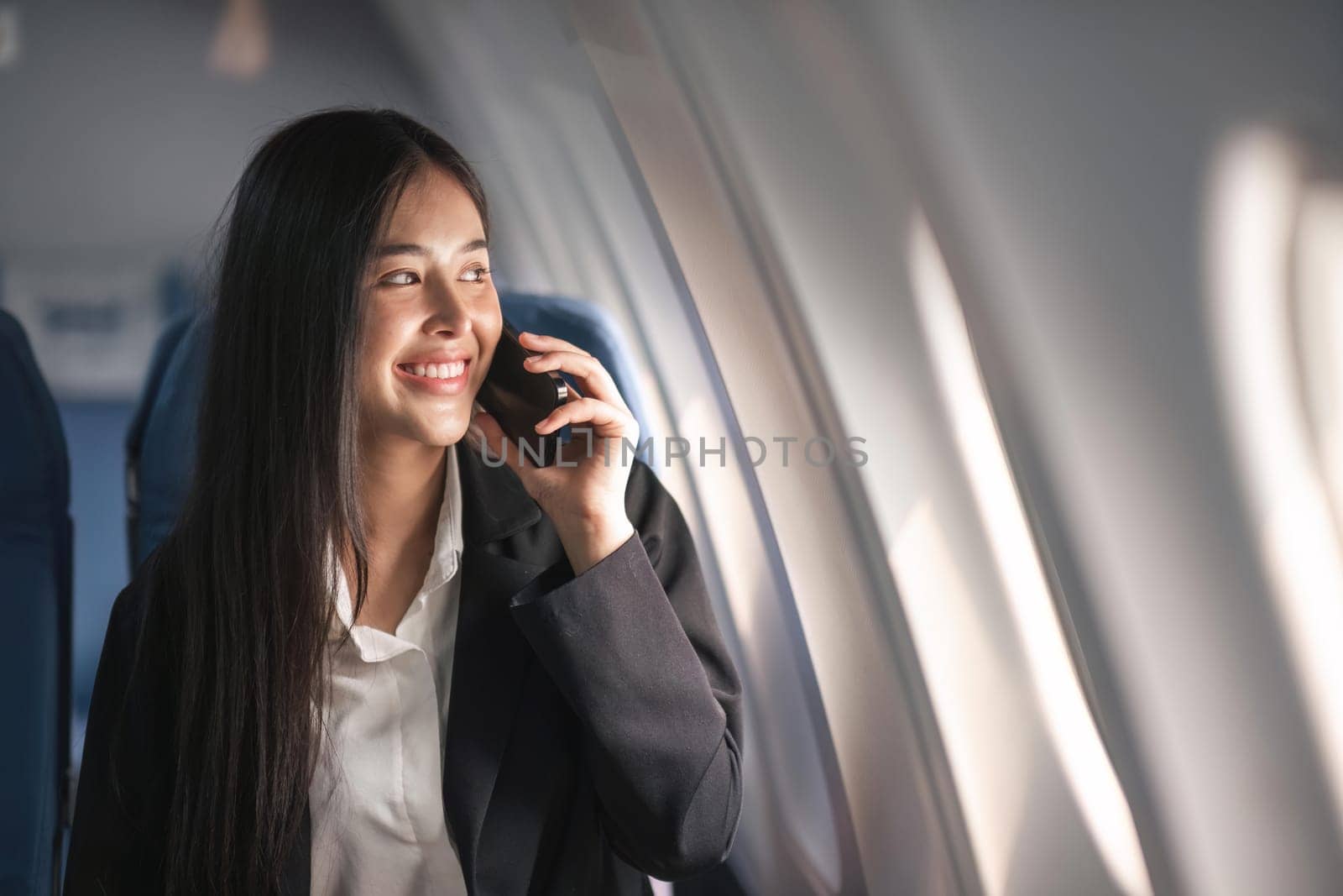 Traveling and technology. Flying at first class. Pretty young business woman using smartphone while sitting in airplane by nateemee