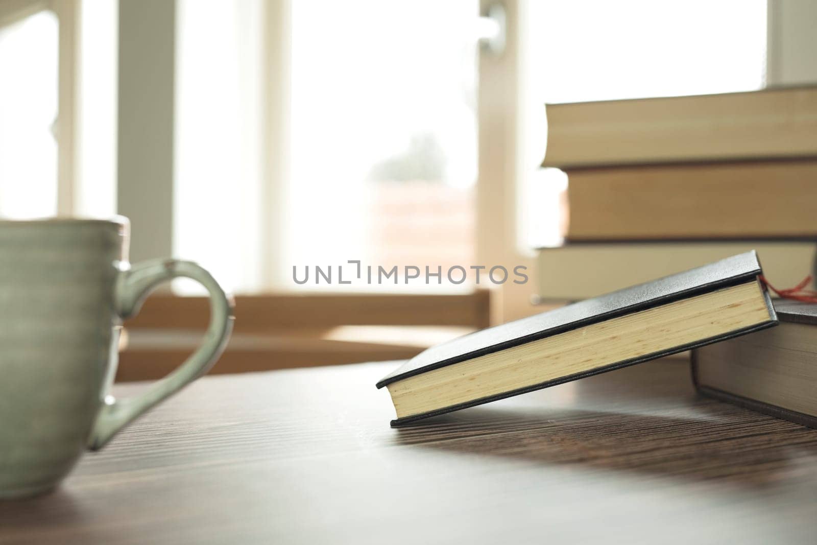 Education learning concept with opening book or textbook at home in office room, stack piles of literature text academic archive on reading desk and aisle of bookshelves in school study class room background interior student