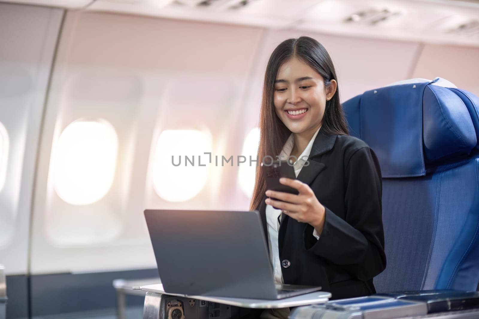 Traveling and technology. Flying at first class. Pretty young business woman using smartphone while sitting in airplane by nateemee