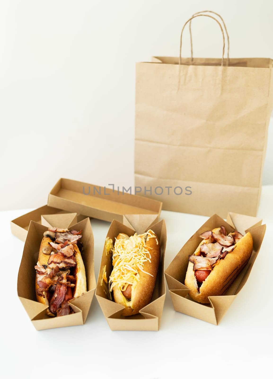 Food delivery concept. Different types of hot dogs in craft packaging on the table, vegan, meat, vegetarian. Street food, junk food. by sfinks