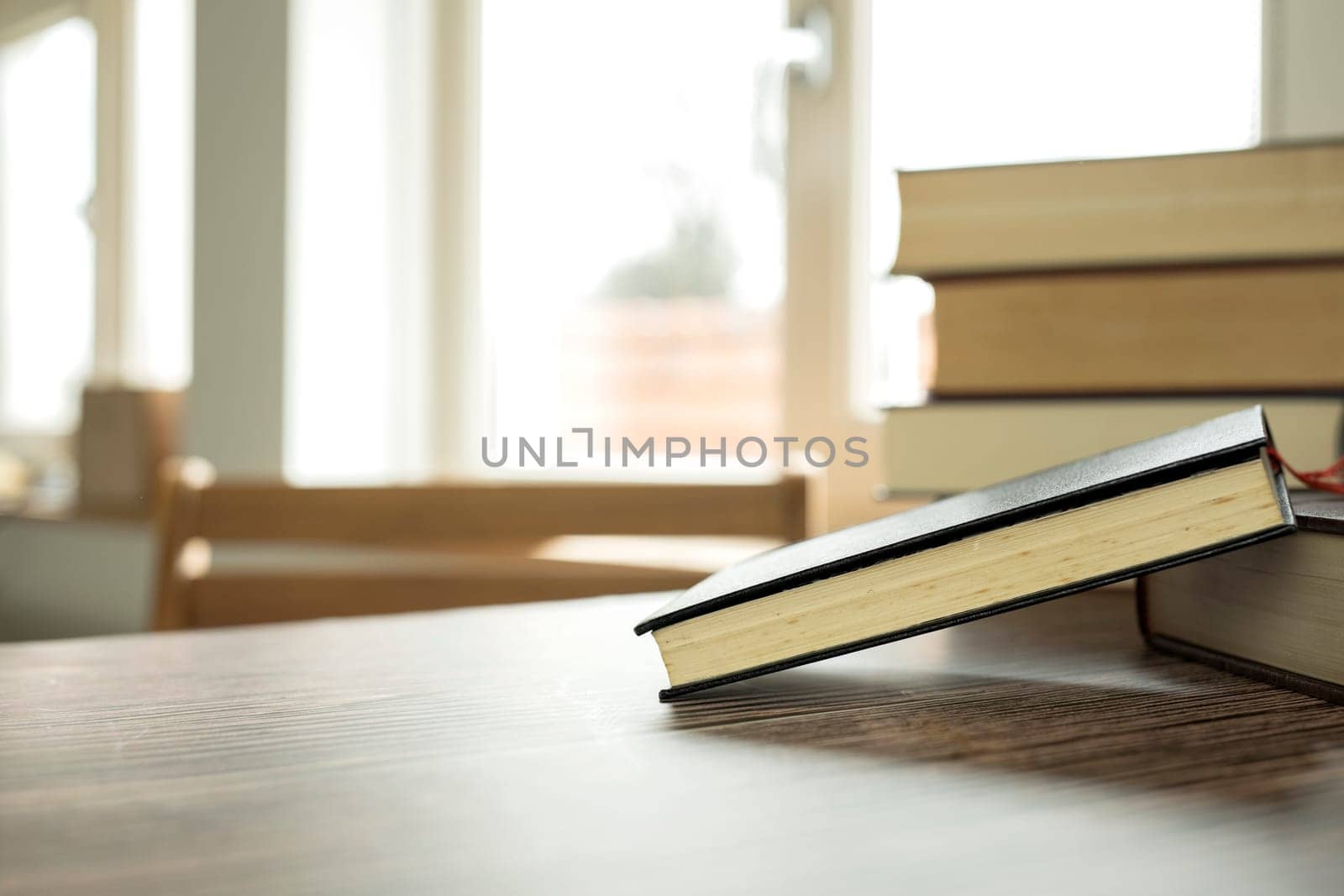 Education learning concept with opening book or textbook at home in office room, stack piles of literature text academic archive on reading desk and aisle of bookshelves in school study class room background interior student