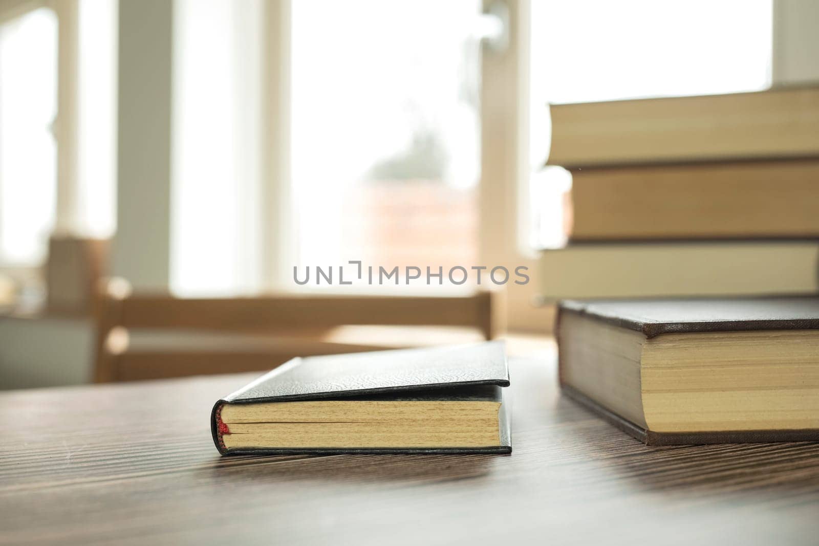 Education learning concept with opening book or textbook at home in office room, stack piles of literature text academic archive on reading desk and aisle of bookshelves in school study class room background interior by Annebel146