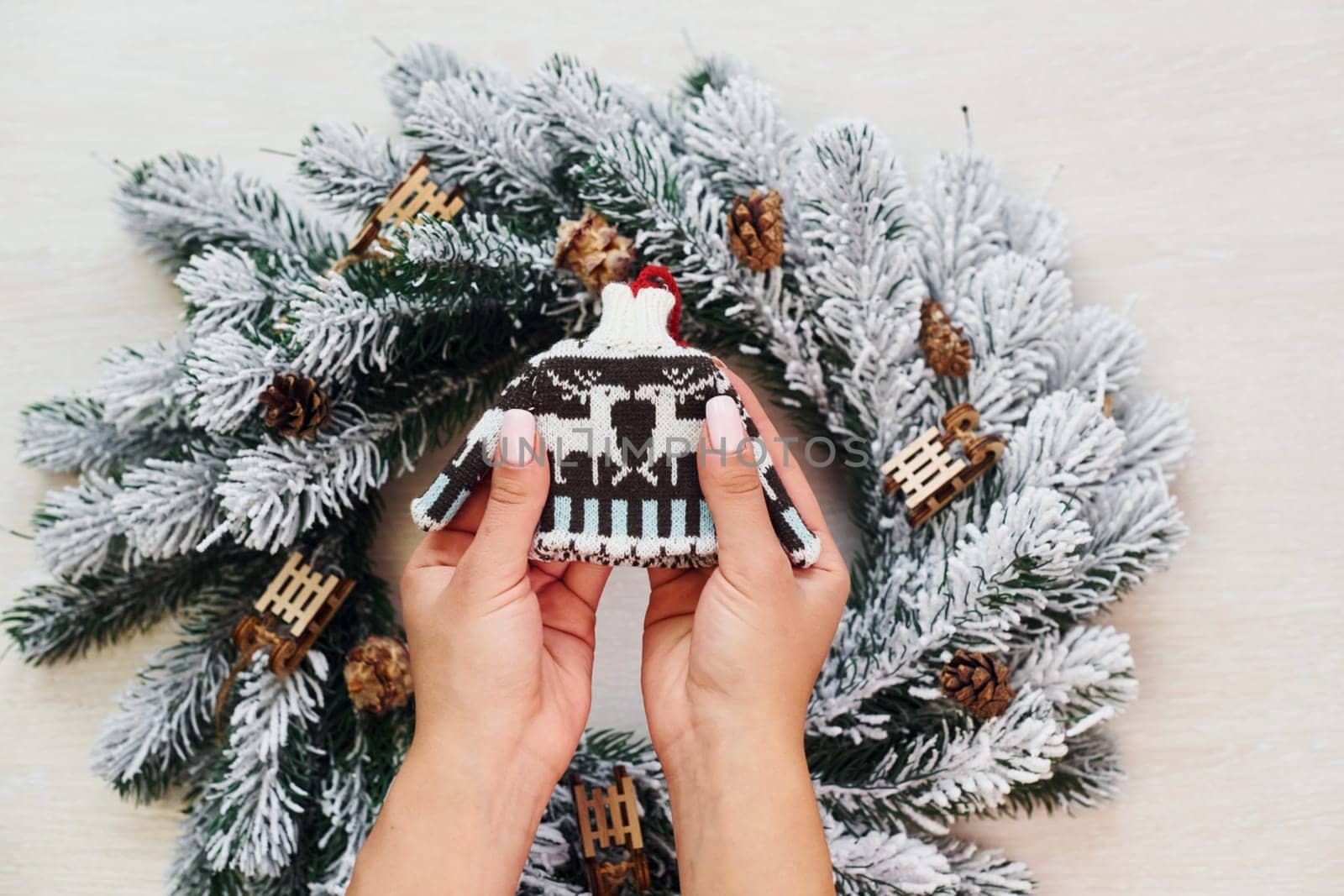 Woman's hands holds little sweater. Top view of christmas festive texture with new year decorations by Standret