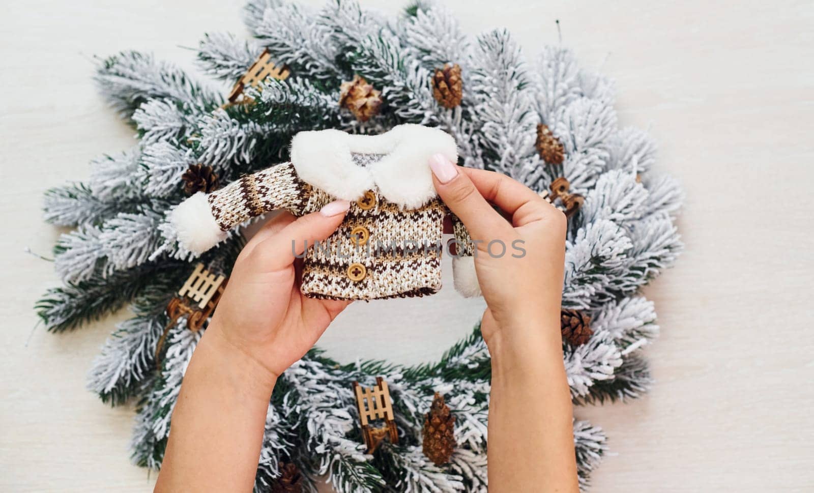 Woman's hands holds little sweater. Top view of christmas festive texture with new year decorations by Standret