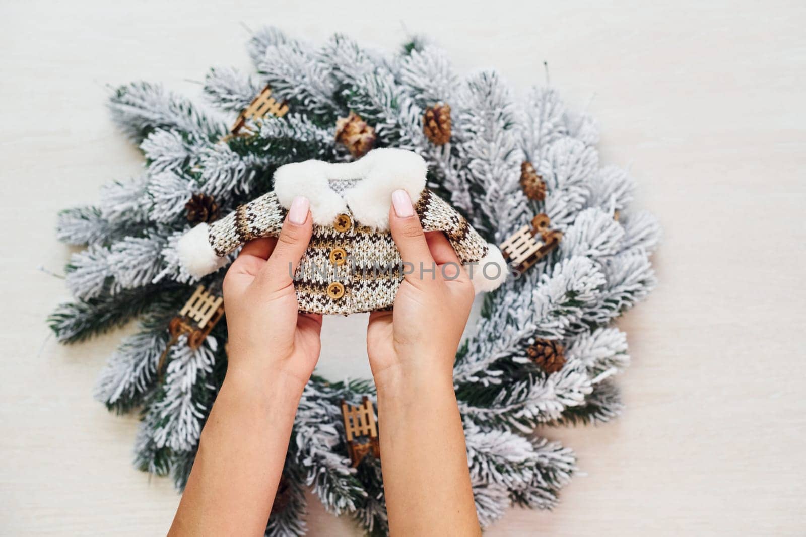 Woman's hands holds little sweater. Top view of christmas festive texture with new year decorations by Standret