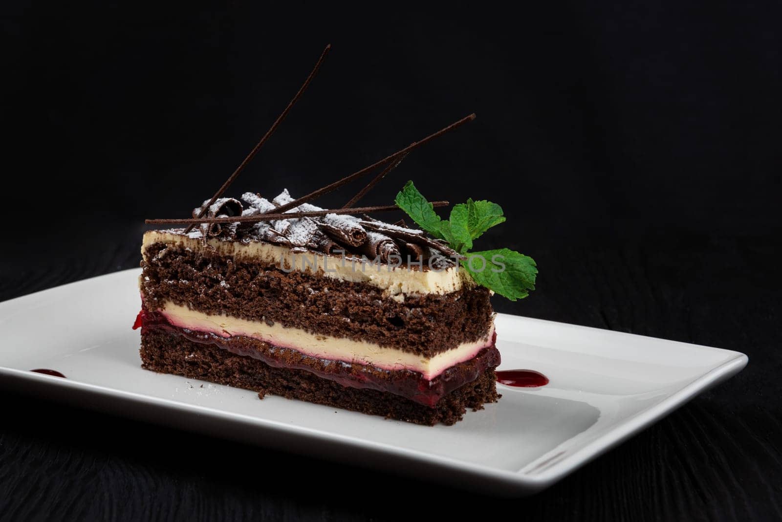 Chocolate cake decorated with mint leaves on black background