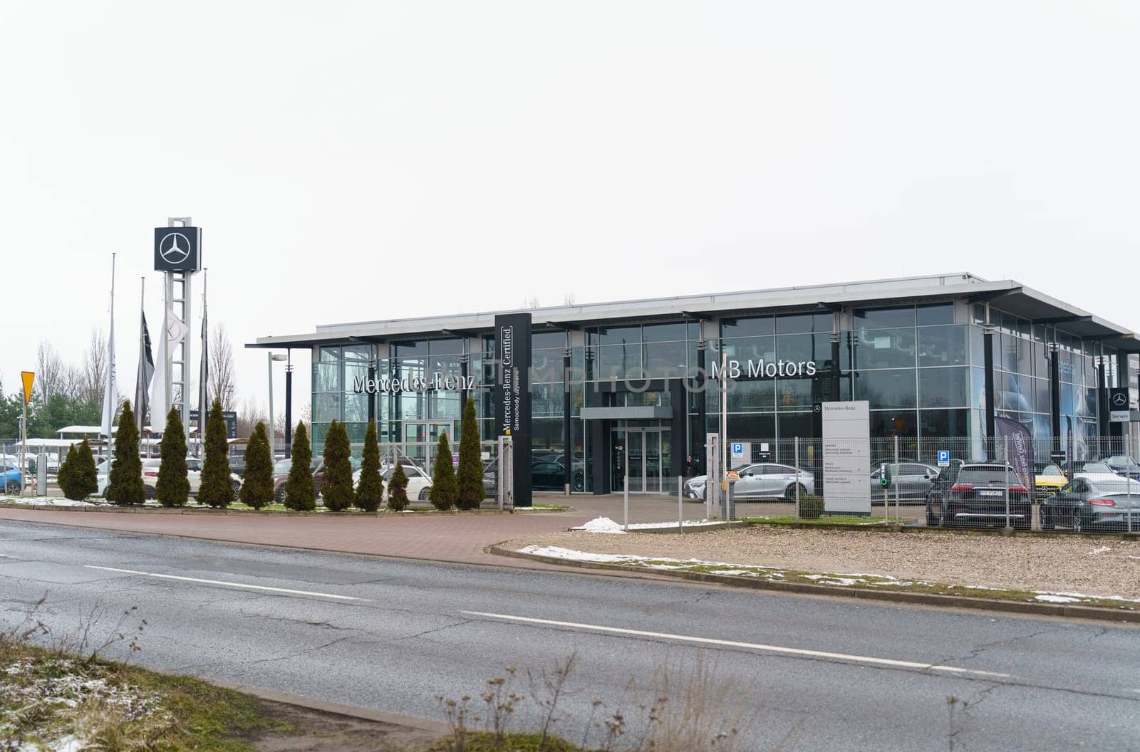 Poznan, Poland - January 25, 2023: Mercedes Benz car showroom, next to it behind a mesh fence are new cars.